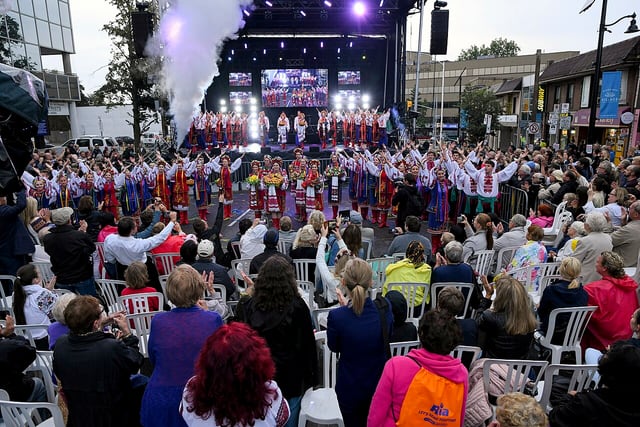 Velká skupina tanečníků v ukrajinských krojích vystupuje před publikem na venkovním festivalu.
