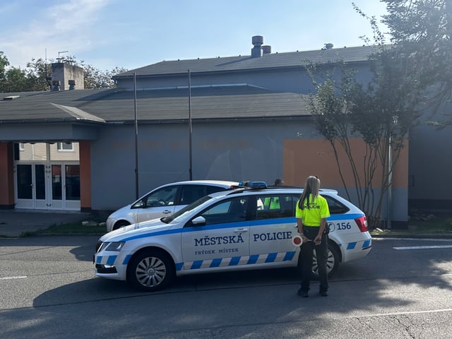 Bílé služební vozidlo Městské policie Frýdek-Místek zaparkované před budovou.